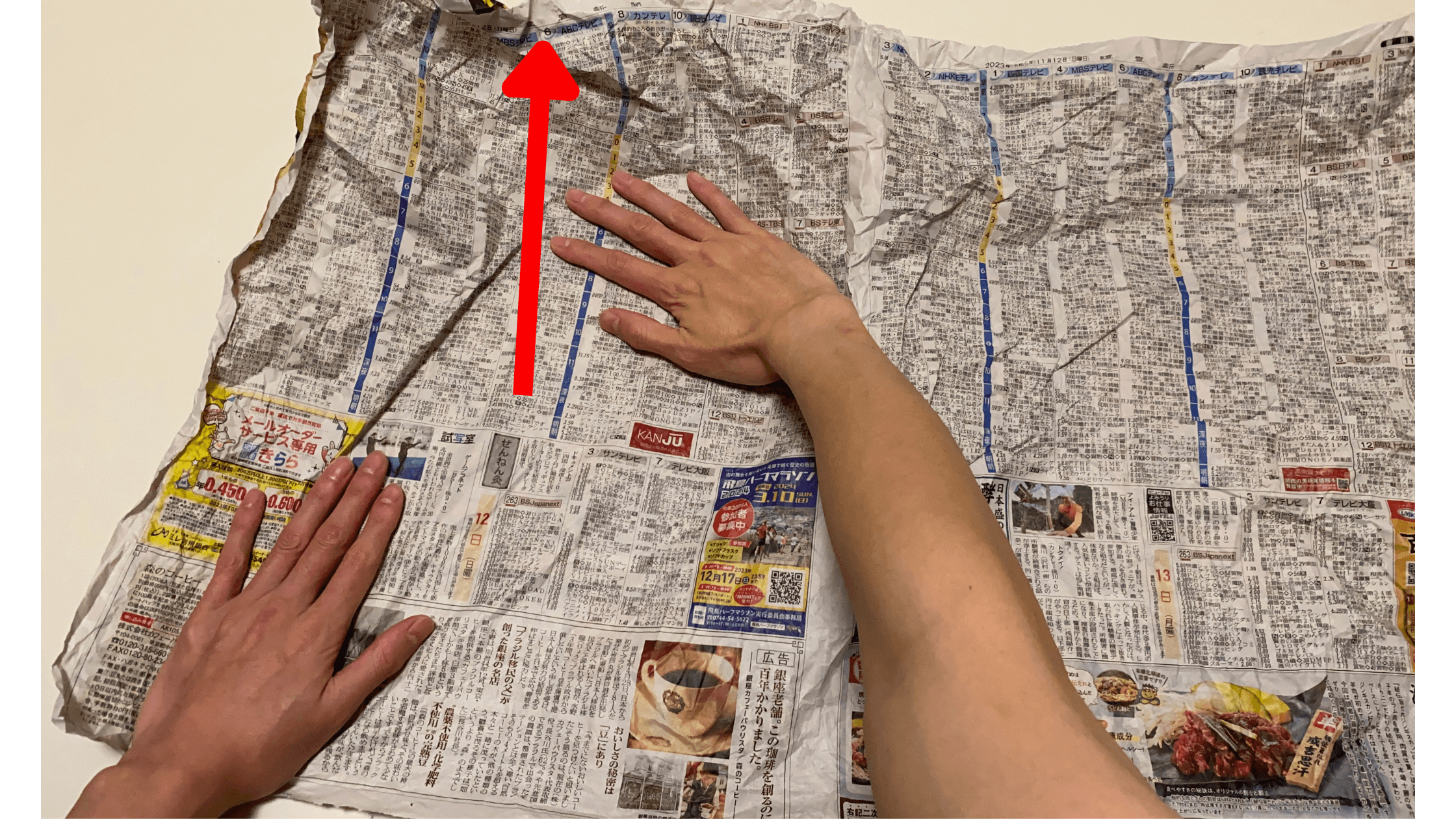 新聞紙を前に向かって広げます。